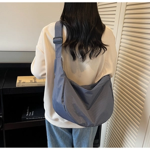 Dettaglio della borsa hobo a quadretti blu con tracolla larga regolabile sulla modella