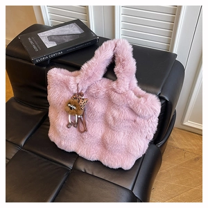 Sac cabas rose en fausse fourrure avec breloque d'ours, posé sur un canapé chic