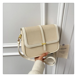 Detail of cream woven shoulder bag with gold twist lock and white leather trim