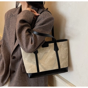 Detail einer großen beigen Canvas-Tasche mit schwarzen Lederbesätzen an der Schulter