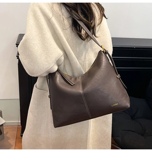Detailed view of dark brown leather tote bag with white contrast stitching and gold logo