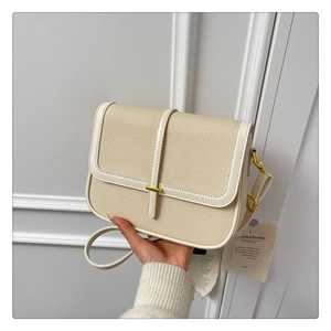 Detail of light beige woven crossbody bag with white leather trim and gold metal lock clasp