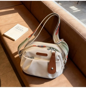 Close-up of pleated beige nylon crossbody bag with floral strap and leather brand logo