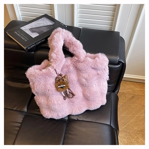 Détail d'un sac cabas en fausse fourrure rose avec breloque d'ours en peluche doux