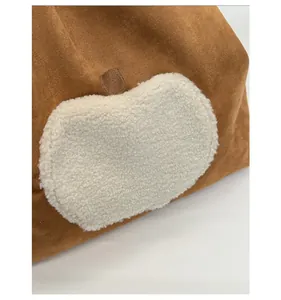 Detail showing high-quality brown suede fabric and soft white sherpa apple patch texture