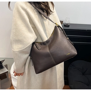 Detail of dark brown tote bag with contrast stitching and golden zipper on model