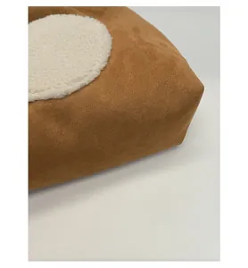 Detail of reinforced bottom on brown suede tote with white plush decorative patch
