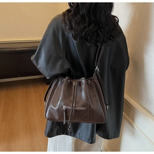 Détail du sac seau matelassé marron foncé avec œillets métalliques et cordon