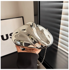 Close-up of a silver mirror-finish acrylic clutch bag with a metal chain strap