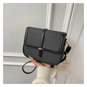 Close-up of black and grey denim crossbody bag with gold hardware buckle and leather trim