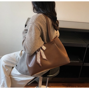 Brown leather tote bag with elegant patterned scarf detail shown in side shoulder view