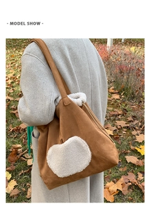 Brown faux suede tote bag with white faux fur heart patch shown in an outdoor setting