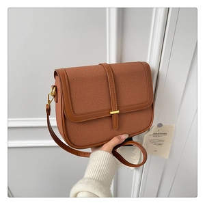 Detail of a brown woven shoulder bag with faux leather flap and gold metal buckle