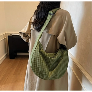 Dettaglio della borsa hobo a quadri verdi indossata da modella con cappotto kaki