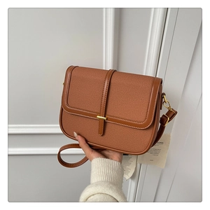 Close-up of retro brown crossbody bag with textured fabric and golden lock detail