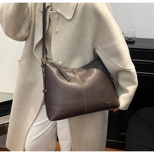 Detail of dark brown tote bag showing litchi grain leather texture and tassel zipper