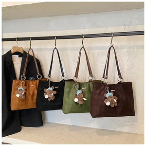 Detail of four large woven tote bags in brown, black, green and coffee with bear charms