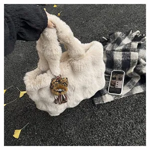 Gros plan d'un sac cabas en fausse fourrure avec charm ours sur des feuilles d'automne