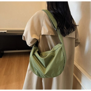 Borsa a tracolla a quadretti verdi e bianchi con tracolla larga indossata su un cappotto