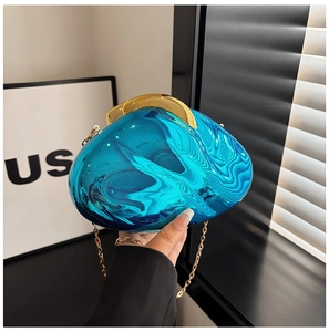 Detail view of bright blue acrylic evening clutch with wavy texture and gold metal chain
