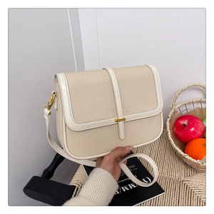 Detail of minimalist beige canvas and leather crossbody bag with golden buckle on a stool