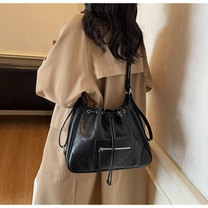 Détails du sac seau noir matelassé avec fermetures éclair argentées et bandoulière