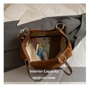 Macro detail of the spacious brown suede tote bag interior with magnetic closure and bear charm