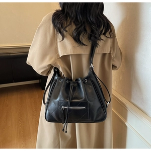 Détail d'un sac seau matelassé noir avec fermeture à cordon et œillets argentés