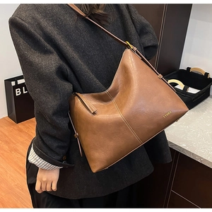 Detail of deep brown tote bag featuring fine leather texture and white contrast stitching