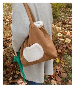 Brown suede tote bag with white plush apple patch shown on model in winter coat