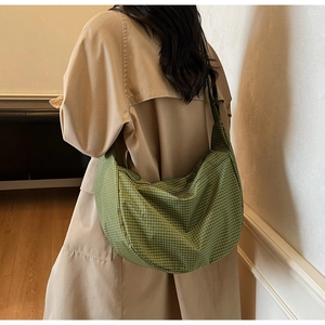 Borsa hobo a scacchi verde indossata da una modella in un interno minimalista