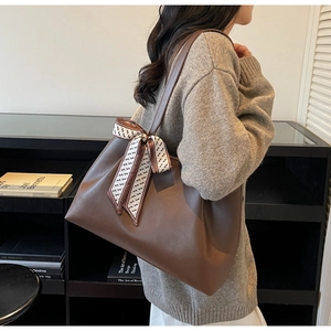 Detail view of large brown tote bag with stylish patterned silk ribbon on strap