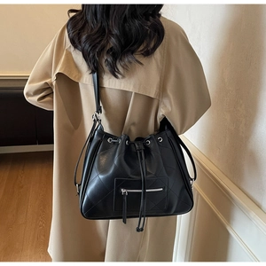 Vue détaillée d'un sac seau en cuir matelassé noir porté par un mannequin en manteau