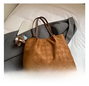 Close-up of brown suede tote bag with quilted diamond pattern and cute bear charm
