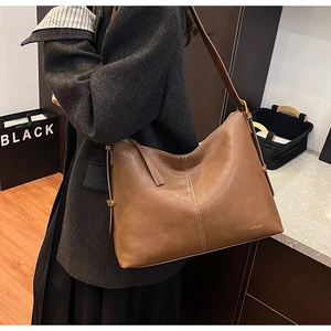 Detailed side view of brown textured leather tote bag with adjustable shoulder strap