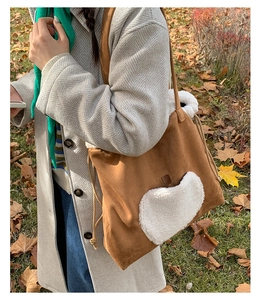 Brown suede tote bag with white fleece decoration and drawstring detail in autumn setting