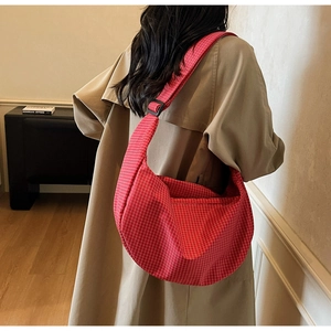 Modella che indossa una borsa a mezzaluna a quadretti rossi con tracolla regolabile per uso quotidiano