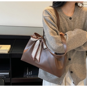 Close-up of brown faux leather tote bag featuring a stylish black and white printed silk scarf
