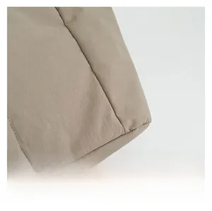 Détail du tissu matelassé beige avec des coutures soignées sur un grand sac cabas