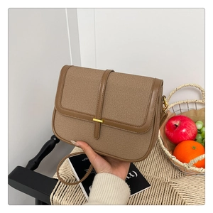 Detail view of brown vintage crossbody bag with gold metal clasp and leather trim accents