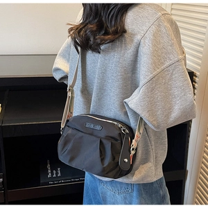 Detailed view of black nylon pleated crossbody bag with stylish wide jacquard shoulder strap
