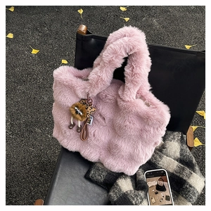 Détail d'un sac cabas rose en peluche avec un pendentif léopard sur une chaise d'hiver