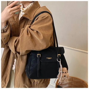 Détail du grand sac cabas en cuir noir avec boucle dorée et charm de petit chien brun