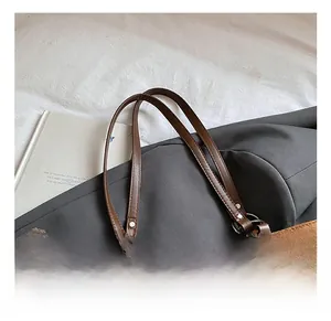 Detail of brown tote bag with quilted texture, leather handles and bear charm