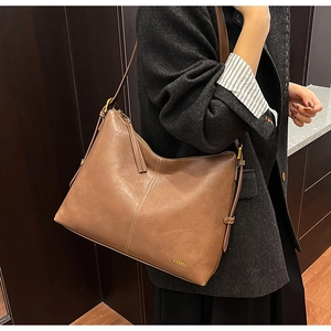 Detail of vintage brown matte leather tote bag featuring vertical stitching and metal logo
