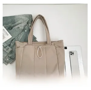 Vue détaillée d'un sac cabas beige matelassé avec poches latérales et détails de cordon