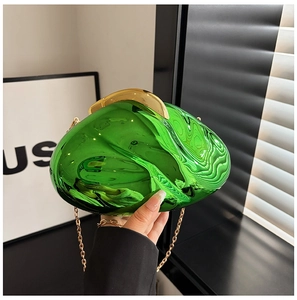 Detailed close-up of emerald green acrylic clutch bag with gold chain and pebble texture