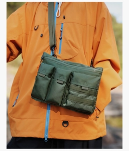 Detail of army green tactical nylon messenger bag with triple front pockets and orange zip cord