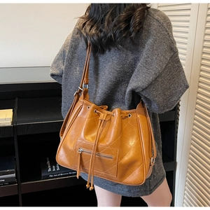 Détail du sac seau matelassé caramel montrant le cordon de serrage et la poche zippée