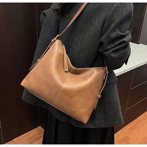 Detail of tan vintage leather shoulder bag with tassels and decorative stitching